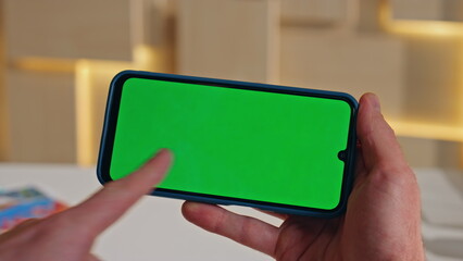 Guy swiping chromakey cellphone watching social media at work break close up.