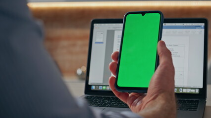 Manager finger swiping mockup cellphone at computer table. Director working
