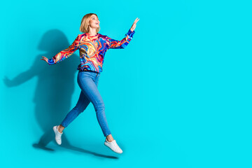 Full size photo of optimistic adorable girl dressed print shirt jeans look at discount empty space isolated on blue color background