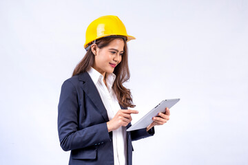 Smiling architect Asian woman wearing black suit and yellow safety helmet using tablet computer standing isolated on gray background.