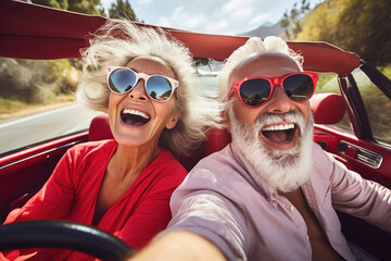 Smiling mature couple riding red retro convertible car outdoors. 