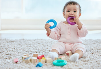 Baby, portrait and playing with toy on floor in home for sensory development, teething progress and...