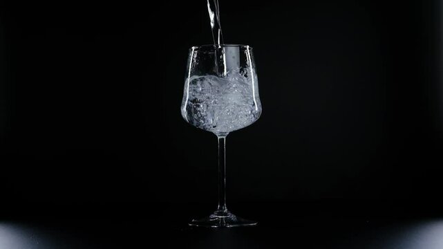 water is poured into a glass on a black background