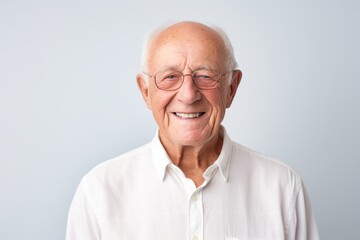 Obraz premium Portrait of a grinning man in his 70s wearing a simple cotton shirt in front of minimalist or empty room background