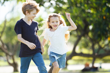 Caucasian white siblings playing at the park in morning.