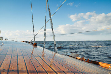 Sailing in a sea in sunny weather. Sky partially covered with clouds, small waves on the surface....