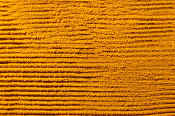 Abstract orange background of spilled turmeric powder, top view