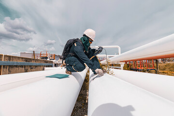 Male worker inspection and measurement thickness pipeline oil and gas at check record pipeline