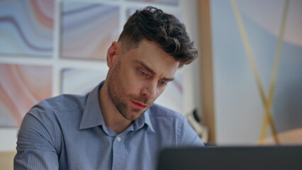 Obraz premium Serious boss looking computer screen at workplace closeup. Man solving tasks