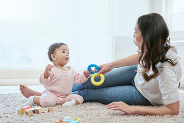 Home, mom and baby with toys for bonding, playing and child development on floor in nursery. Happy,...