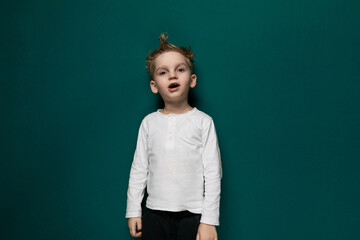 Young Boy Standing in Front of Green Wall