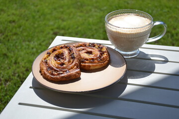 Glass cup of coffee  and  puff pastry outdoor on table in shade