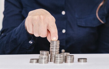 Stacks of coins on the table, finger holding largest stack of coins