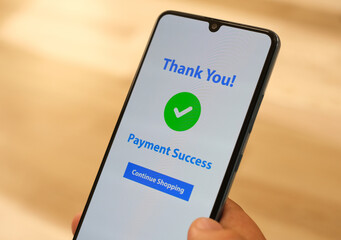 The male hand holding a cell phone with the payment app interface showing the payment successful message with a green check mark. Online shopping, mobile banking and transactions.