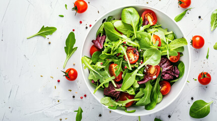 Fresh mixed green salad with cherry tomatoes in a white bowl on a white background