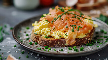 Fresh smoked salmon and scrambled eggs on seeded whole grain toast, garnished with chives and pepper