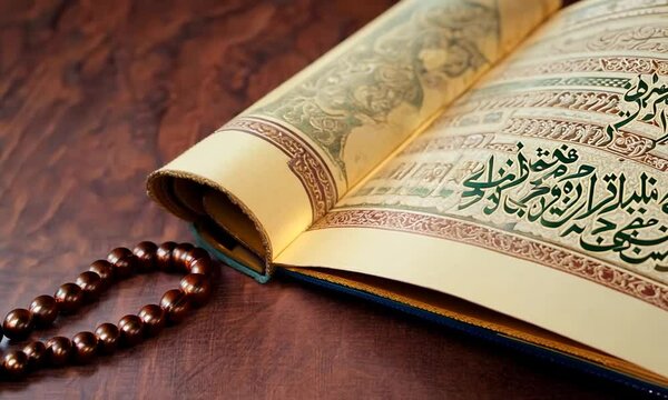 The Holy Al Quran with written Arabic calligraphy meaning of Al Quran and rosary beads or tasbih