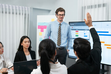 Corporate employee raise hand ask question during project meeting, businessman or manager...