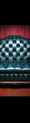 Fototapeta premium Retro royal blue tufted leather chesterfield sofa against red curtain background