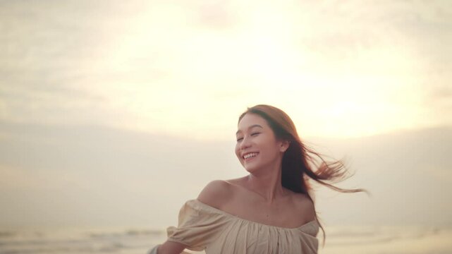 Happy young asian woman with freedom on the sea beach at golden sunset, Female tourist on seaside summer vacation