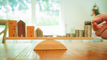 Wood house and Coins stack with balance scale. Money management, financial plan, time value of money. Real estate and property agent offer house concepts.