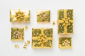 Golden gift boxes and confetti on color background, top view