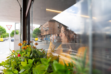 Caucasian woman having tea looking through the window of a coffee shop