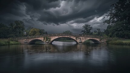 Fototapeta premium Black clouds gather over a picturesque bridge, their shadows deepening the scene's dramatic beauty.