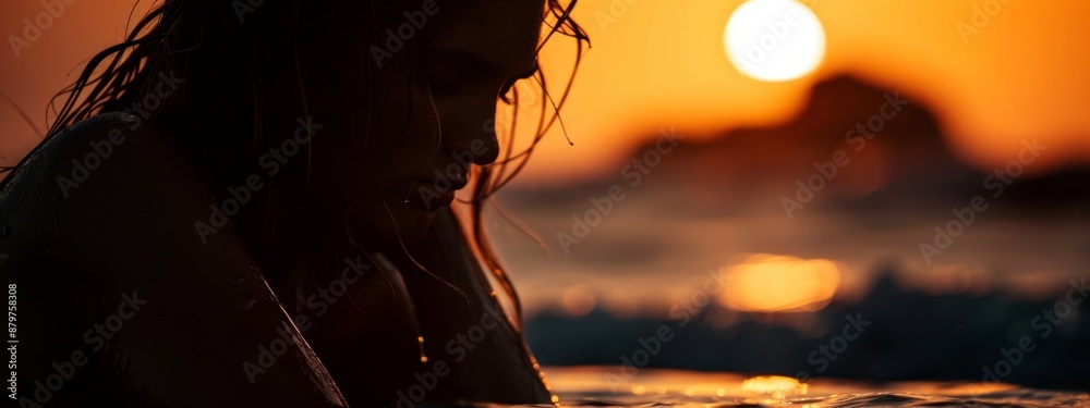 Wall mural a woman atop a surfboard, sunset backdrop, hair billowing in wind