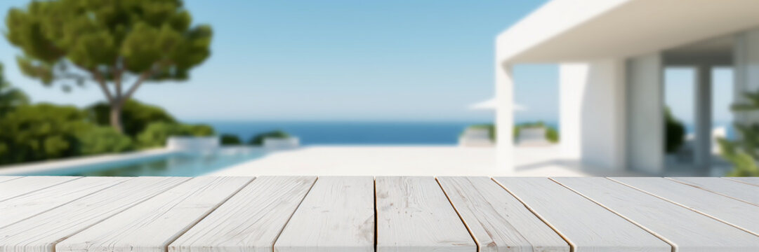 Leerer wei&szlig;er Holztisch vor unscharfem Hintergrund, Terrasse mit Meerblick im Sommer, Luxus Ferienhaus oder Resort im Urlaub mit Platz f&uuml;r Produktpr&auml;sentation oder Text