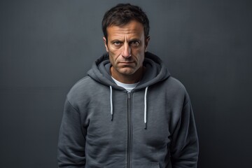 Obraz premium Portrait of a tender man in his 40s wearing a zip-up fleece hoodie while standing against bare concrete or plaster wall