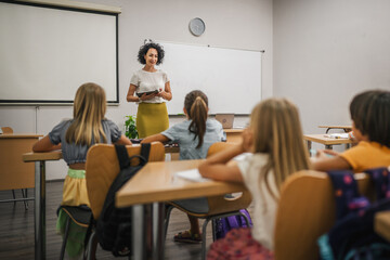 Mature teacher teach a lesson young students and hold tablet