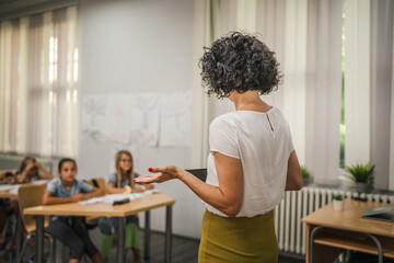 Mature teacher teach a lesson young students and hold tablet