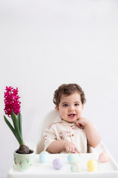 Happy Baby Celebrating Norouz with Decorated Eggs and a Spring Flower