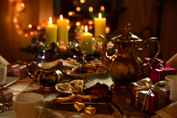 Coffee table set for Christmas. Silver coffee pot, Advent wreath, different home baked christmas cookies on an etagere and small gifts on the table.