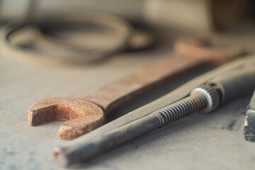 Locksmith tools such as a wrench and an adjustable wrench with selective focus lie on a beige surface and gather dust idle.