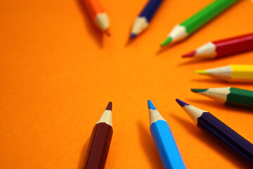 Crayons - colored pencil set loosely arranged on orange background Drawing supplies Pink orange green blue pencil Copy space Back to school concept