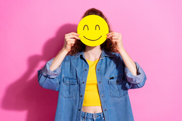 Photo of charming positive girl wear jeans shirt holding smiley cover face empty space isolated pink color background