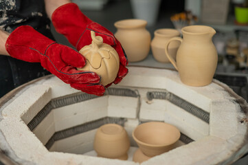 Close-up of a man's hands loading ceramics into a special kiln. 