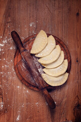 raw chebureks, mini, on a cutting board, wooden table, close-up, no people,