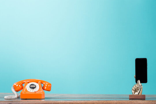 Retro telephone and mobile phone in golden arm front gradient mint blue background. Vintage old style filtered photo. Contact numbers  banner concept
