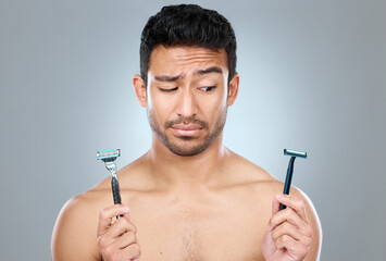 Asian man, shaving and choice with razor blade for grooming, skincare or hair removal on a gray...