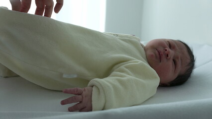 Nurse gently dressing a newborn baby after changing the diaper during hospital care routine. the...