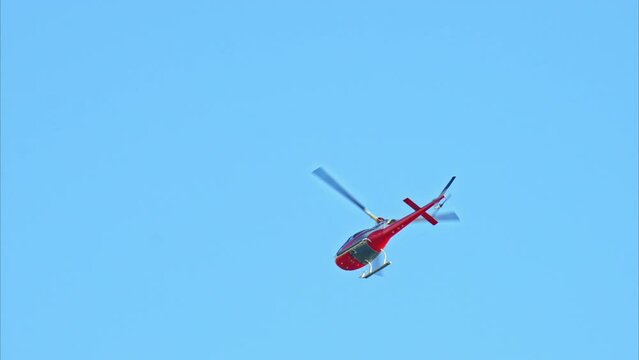 Red helicopter moving in the sky in daylight