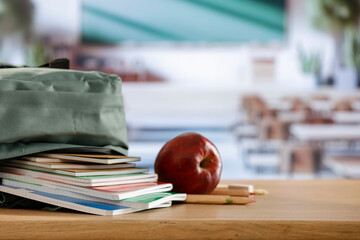 Back to school concept. Wooden desk top with backpack and apple and school stuff with blurred...