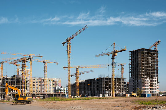 Many high-rise cranes and industrial construction equipment against the backdrop of a construction buildings.
