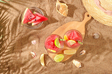 Ice cold homemade lemonade or cocktail with mint, watermelon and fruits on the sandy beach, refreshing summer drink recipe, detox diet and weight loss concept, menu for restaurant,