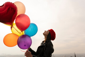 woman holding colorful balloons against the sky