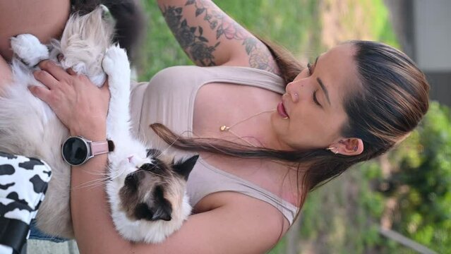 Woman cuddling her fluffy ragdoll cat outdoors in a sunny garden, conveying warmth and companionship