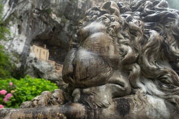 Entrance to the Covadonga cave and hermitage, framed by lush greenery and a lion statue in Asturias, Spain